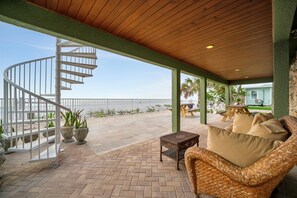A covered outdoor area with a spiral staircase, wicker furniture, and potted plants. - Stones Throw Beachfront Luxury Suites (Indian Rocks Beach)