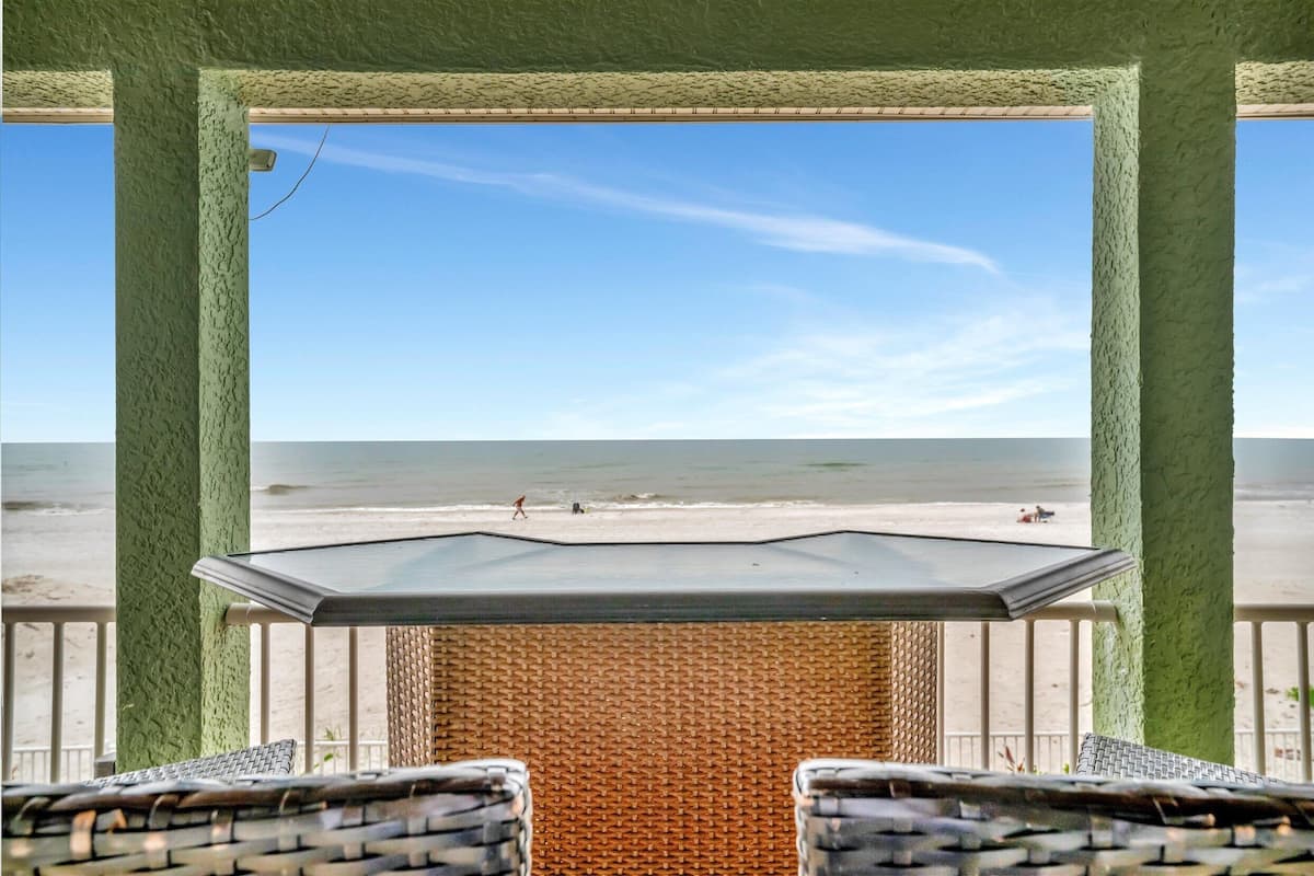 Un balcón con mobiliario de mimbre con vistas a una playa.