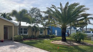 A residential area with paved walkways, palm trees, and houses with blue and beige exteriors. - Paradise palms 3 (Port St. Lucie)