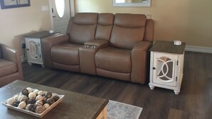 A living room with a brown leather sofa, a small side table, a white cabinet, and a coffee table with decorative items. - Paradise palms 3 (Port St. Lucie)