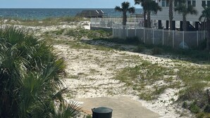 A beachfront property with a white building, a fenced area, and a clear view of the ocean.