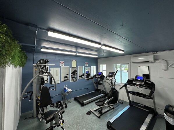 Une salle de sport équipée de tapis de course, d’un banc de musculation et d’autres appareils d’exercice.