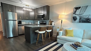 A modern kitchen with dark cabinets, stainless steel appliances, and a central island with stools.