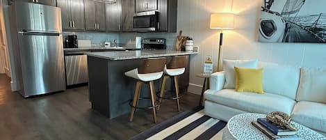 A modern kitchen with dark cabinets, stainless steel appliances, and a central island with stools.