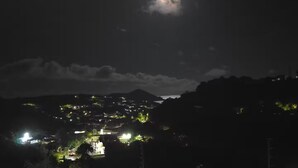 A nighttime view of a town with a prominent hill in the background and a bright moon in the sky. - Charming 2- Bedroom Apartment with AC, WiFi in St Thomas' East End (St Thomas)