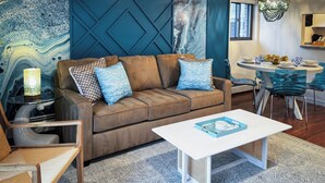 A modern living room with a brown leather sofa, blue and white cushions, a white coffee table, and a blue and white patterned rug.