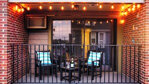 A balcony with two chairs, a table, and a bottle of wine.