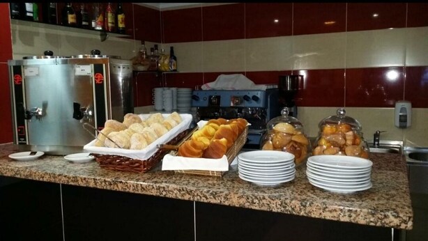A breakfast buffet with various pastries and bread, a coffee machine, and a refrigerator in a kitchen setting. - Residencial Pinto  (Guarda)
