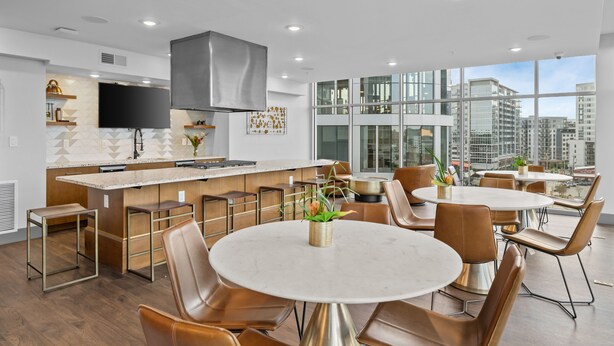 A modern kitchen with a large island, bar seating, and a dining area with round tables and chairs. - Music City Maverick - Walk to Broadway, Pool, Gym (Nashville)