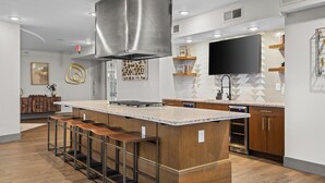 A modern kitchen with a central island, bar stools, a stainless steel range hood, and built-in appliances. - Music City Maverick - Walk to Broadway, Pool, Gym (Nashville)