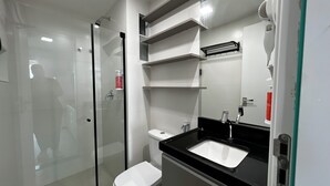 A modern bathroom with a glass-enclosed shower, a white toilet, and a black sink with a mirror above it. - RN STUDIO - APTO 1018 (Maceio)