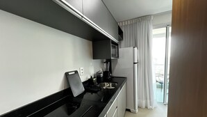 A modern kitchen with black countertops, a built-in oven, a coffee maker, and a refrigerator. - RN STUDIO - APTO 1018 (Maceio)