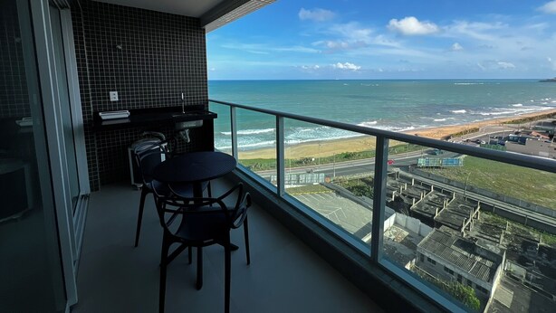 A balcony with a view of the ocean, a small table, and two chairs. - RN STUDIO - APTO 1018 (Maceio)