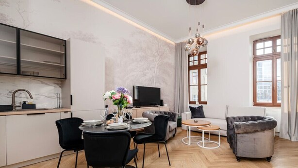 Un espacio habitable moderno con comedor, sofá, televisor y cocina.