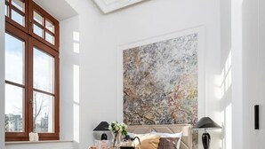 Un dormitorio con una cama grande, una mesita de noche, una lámpara, una ventana y un cuadro en la pared.