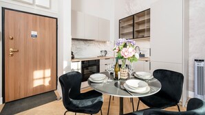 Una cocina moderna con armarios blancos, una salpicadera de mármol y un comedor con una mesa redonda y sillas negras.