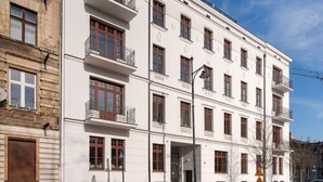 Un edificio de varios pisos con fachada blanca, varios balcones y cielo despejado.