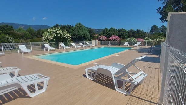 A pool area with lounge chairs and a view of mountains. - Mini-villa 2 pers. 3★ with garden, Residence with swimming pool - Near beaches (Lecci)