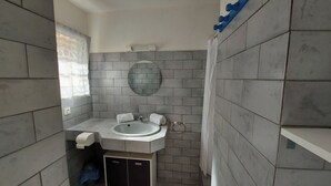 A bathroom with grey tiled walls, a white sink, and a mirror. - Mini-villa 2 pers. 3★ with garden, Residence with swimming pool - Near beaches (Lecci)