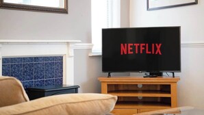 A living room with a television displaying the Netflix logo, a fireplace, and a blue-tiled wall. - 3 Bedroom in Haughton Road with Free WiFi (Darlington)
