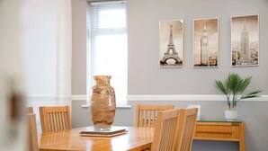 A dining area with a wooden table, chairs, a vase, and three framed pictures of famous landmarks. - 3 Bedroom in Haughton Road with Free WiFi (Darlington)