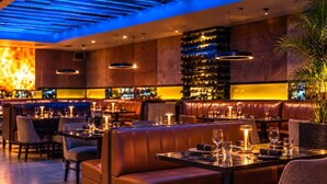 A restaurant with leather booths, tables set with wine glasses, and a bar area with shelves of bottles. - Beachfront Luxury Condo Pool   Walk 2 eat (Carolina)