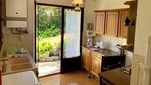 A compact kitchen with a sink, countertop, and wooden cabinets. - Stone house: garden & mountain view (Cipières)