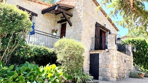 Un bâtiment en pierre doté d’un balcon, d’une porte et de plantes en pot.