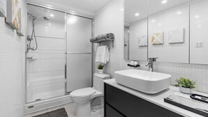 Un bagno moderno con doccia a filo pavimento, un water, un lavandino e uno specchio grande.