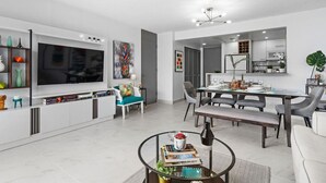 Un soggiorno moderno con una grande TV, un'area pranzo e una cucina.