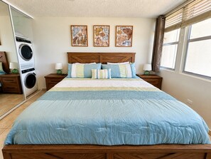 A bedroom with a large bed, a washing machine, and three wall-mounted artworks. - Beachfront Gem Walk 2 Eat W/D (Carolina)