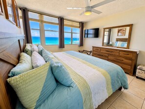 A bedroom with a bed, a dresser, a television, and a large window with a view of the ocean. - Beachfront Gem Walk 2 Eat W/D (Carolina)