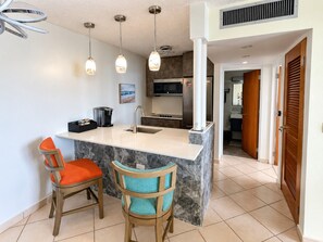 A kitchen with a marble island, two bar stools, a microwave, and a sink. - Rare Find! Beachfront * King Bed W/D  Walk 2 Dine (Carolina)