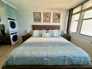 Ein Schlafzimmer mit einem großen Bett, einer Waschmaschine und drei abstrakten Gemälden an der Wand.