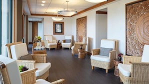 Eine geräumige Lobby mit Korbmöbeln, einer großen Holzverkleidung und einer Decke mit eingelassener Beleuchtung.