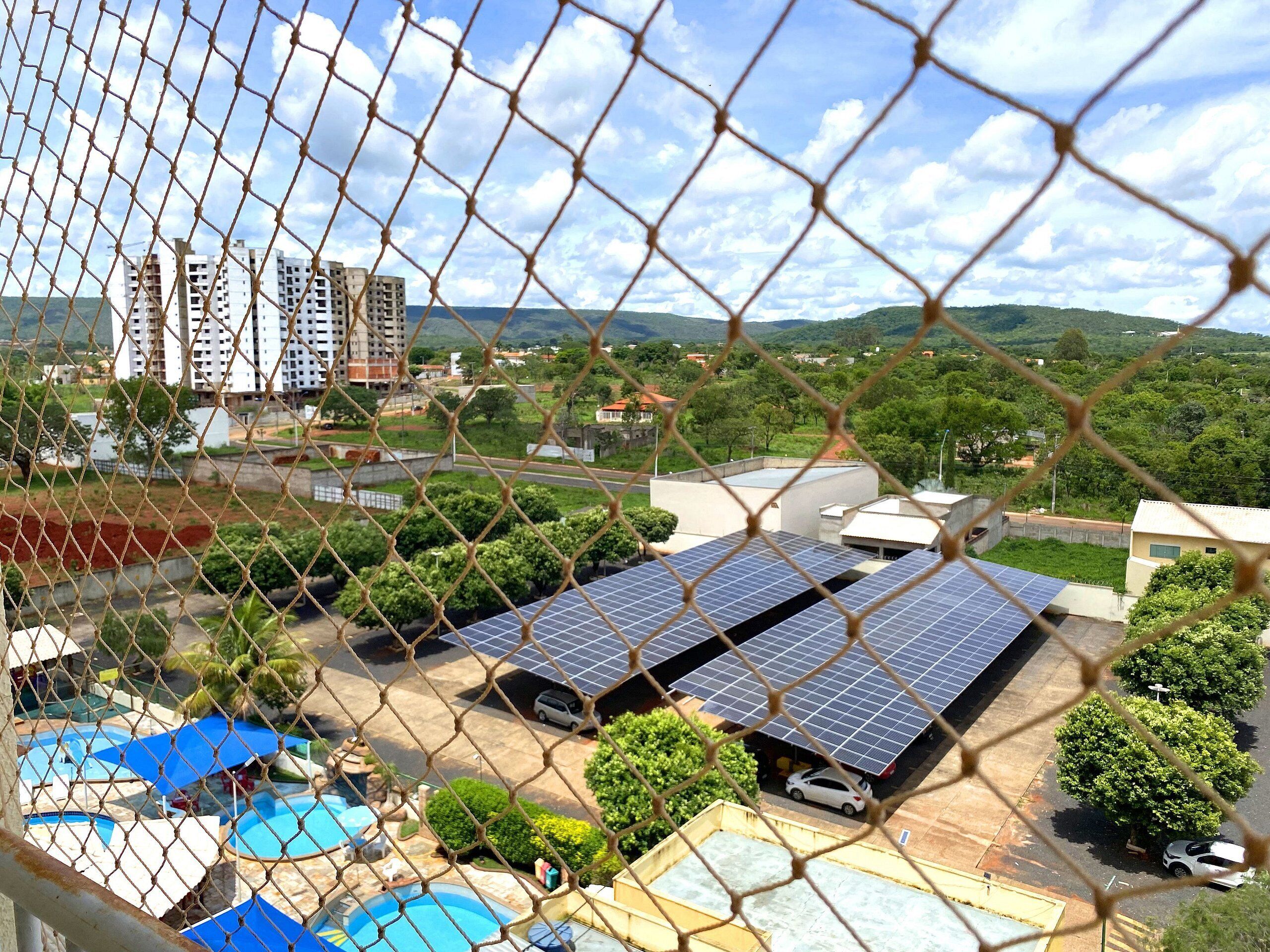 A residential area with solar panels, a swimming pool, and a view of distant buildings.