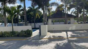 A gated parking area with palm trees and a small pavilion.