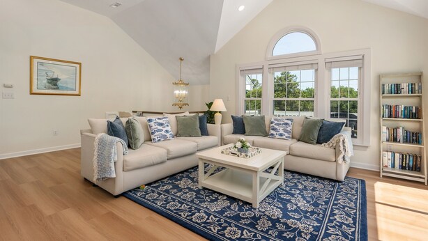 A spacious living room with a large sectional sofa, a coffee table, and a bookshelf. - Walk to Beach, Heated Pool, Hot Tub, Dogs OK! (Kitty Hawk)