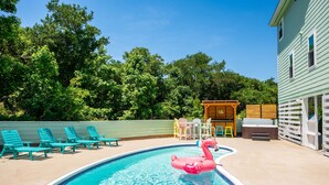 A swimming pool with a pink flamingo float, surrounded by lounge chairs and a hot tub. - Walk to Beach, Heated Pool, Hot Tub, Dogs OK! (Kitty Hawk)
