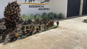 Señal de 'Port Sole Residencial Rocinasa', con una palmera y suculentas al frente.