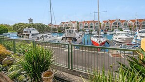 A marina with multiple boats docked, a clock tower, and a row of residential buildings in the background.