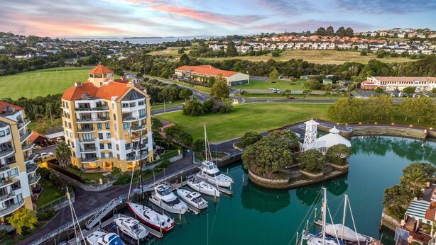 A marina with boats, a building with balconies, and a view of a residential area.