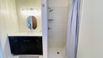 A bathroom with a shower, a sink, and a mirror.