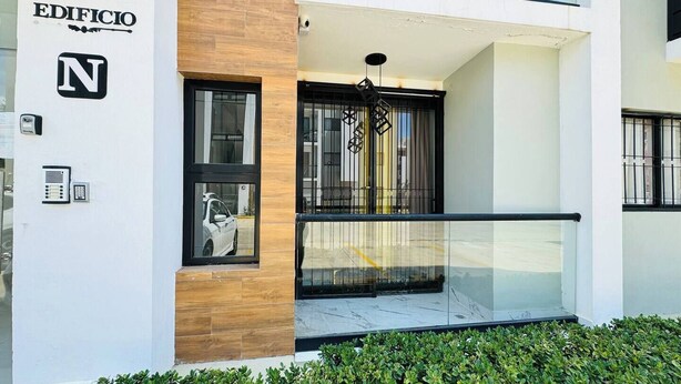 Fachada moderna de un edificio con un llamativo letrero que dice 'EDIFICIO', un buzón y una cámara de seguridad.