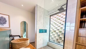 Un baño moderno con tocador de madera, un espejo grande, un lavabo de piedra y una ducha con pared de piedra.