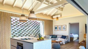 Un espacio moderno con zona de estar, isla de cocina, asientos y dormitorio.