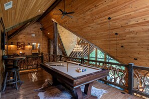 A wooden interior with a pool table, seating area, and a view through a window. - Nite Owl-Luxury Log Cabin Rental, Outdoor Fire Pit, Fire Place, High Speed Internet, Hot Tub, Pool Table, Open Concept- Nantahala NC (Topton)