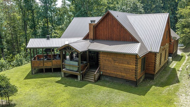 A large wooden cabin with a covered porch and a separate building with a sloped roof. - Nite Owl-Luxury Log Cabin Rental, Outdoor Fire Pit, Fire Place, High Speed Internet, Hot Tub, Pool Table, Open Concept- Nantahala NC (Topton)