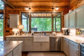 A kitchen with wooden walls, a large window, and a stainless steel dishwasher. - Nite Owl-Luxury Log Cabin Rental, Outdoor Fire Pit, Fire Place, High Speed Internet, Hot Tub, Pool Table, Open Concept- Nantahala NC (Topton)