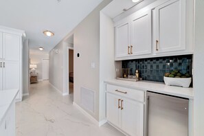 Una cocina moderna con armarios blancos, salpicadero de azulejos y un refrigerador de acero inoxidable.